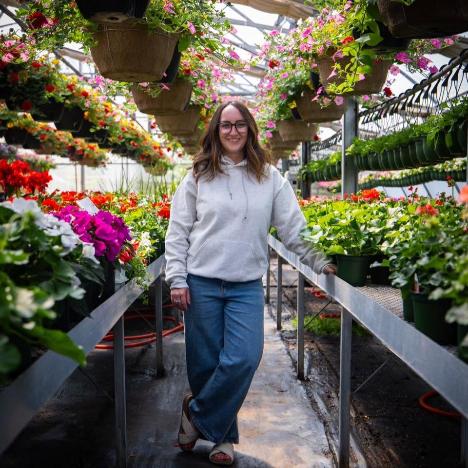 Samantha Turner in a greenhouse full of spring flowers